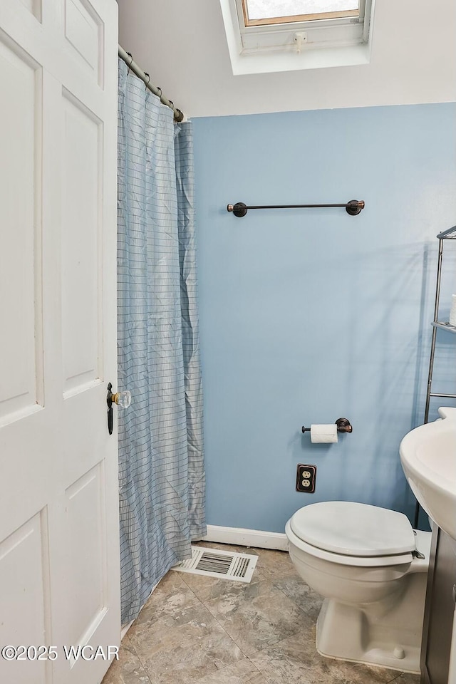 bathroom with toilet and a skylight