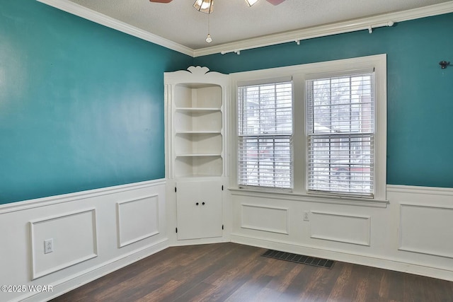 unfurnished room with built in shelves, a textured ceiling, ornamental molding, dark hardwood / wood-style flooring, and ceiling fan