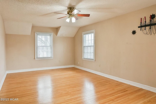 additional living space with ceiling fan, lofted ceiling, plenty of natural light, and light wood-type flooring