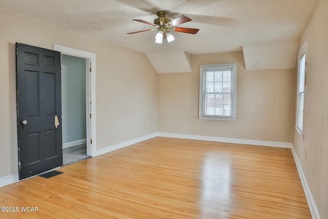 additional living space with ceiling fan, lofted ceiling, light hardwood / wood-style flooring, and a textured ceiling