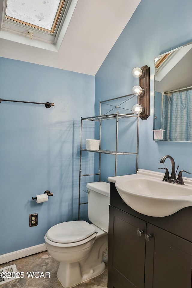 bathroom featuring toilet, tile patterned floors, vanity, and lofted ceiling with skylight