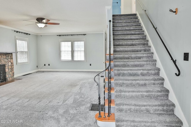 staircase featuring crown molding, a fireplace, carpet flooring, and a wealth of natural light