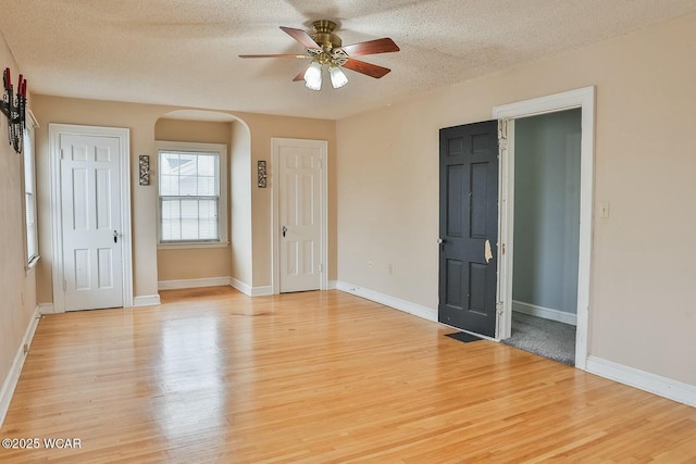 spare room with ceiling fan, a textured ceiling, and light wood-type flooring