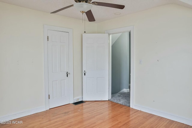 unfurnished bedroom with lofted ceiling, hardwood / wood-style floors, a textured ceiling, and ceiling fan