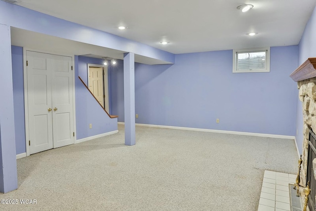 basement with light colored carpet and a fireplace