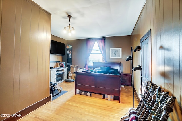 home office featuring a notable chandelier, wooden walls, and light wood-type flooring