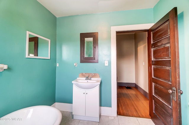 bathroom with tile patterned flooring, vanity, and a washtub