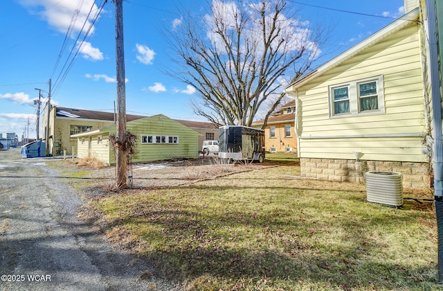 view of yard featuring an outbuilding, a garage, and central AC