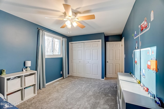 bedroom featuring a closet, baseboards, light colored carpet, and ceiling fan