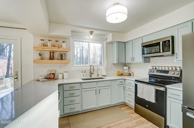 kitchen featuring backsplash, appliances with stainless steel finishes, light countertops, and a sink