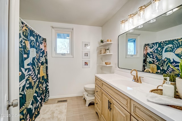 full bathroom with toilet, plenty of natural light, vanity, and baseboards