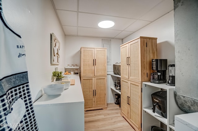 kitchen with light countertops, a paneled ceiling, light wood finished floors, and light brown cabinetry