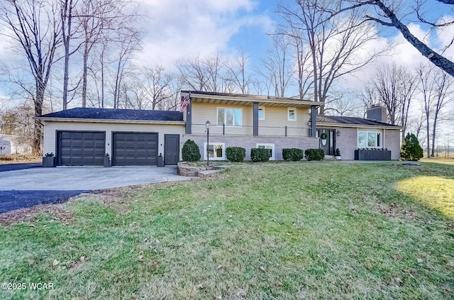 tri-level home with aphalt driveway, cooling unit, a front yard, an attached garage, and a chimney