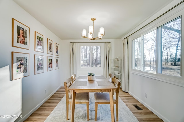 dining area featuring a chandelier, visible vents, light wood-style flooring, and baseboards