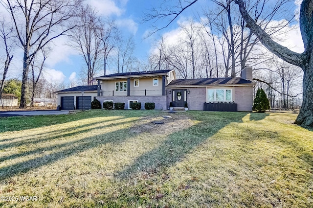 view of front of property with brick siding, a front yard, a chimney, driveway, and an attached garage