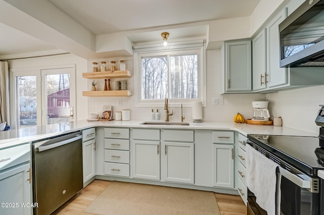 kitchen featuring light wood-style flooring, a sink, stainless steel appliances, light countertops, and decorative backsplash