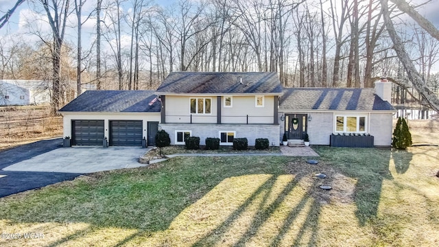 split level home featuring a front yard, an attached garage, driveway, and a chimney