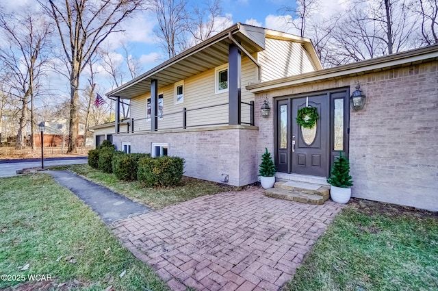 doorway to property featuring a yard and brick siding