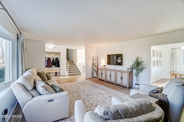 living area with light wood-type flooring and stairway