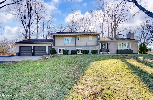 tri-level home featuring a garage, driveway, a chimney, and a front lawn