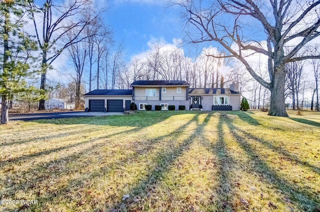 back of house with an attached garage, a lawn, driveway, and a chimney