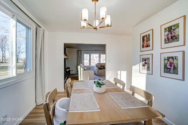 dining room with a chandelier, baseboards, and wood finished floors