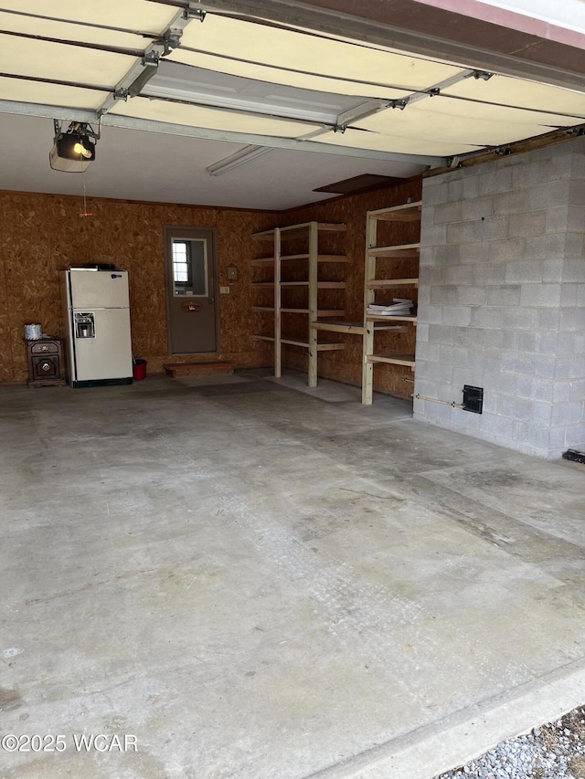 garage with a garage door opener and white fridge