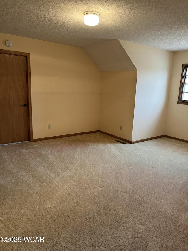 bonus room featuring vaulted ceiling, light carpet, and a textured ceiling