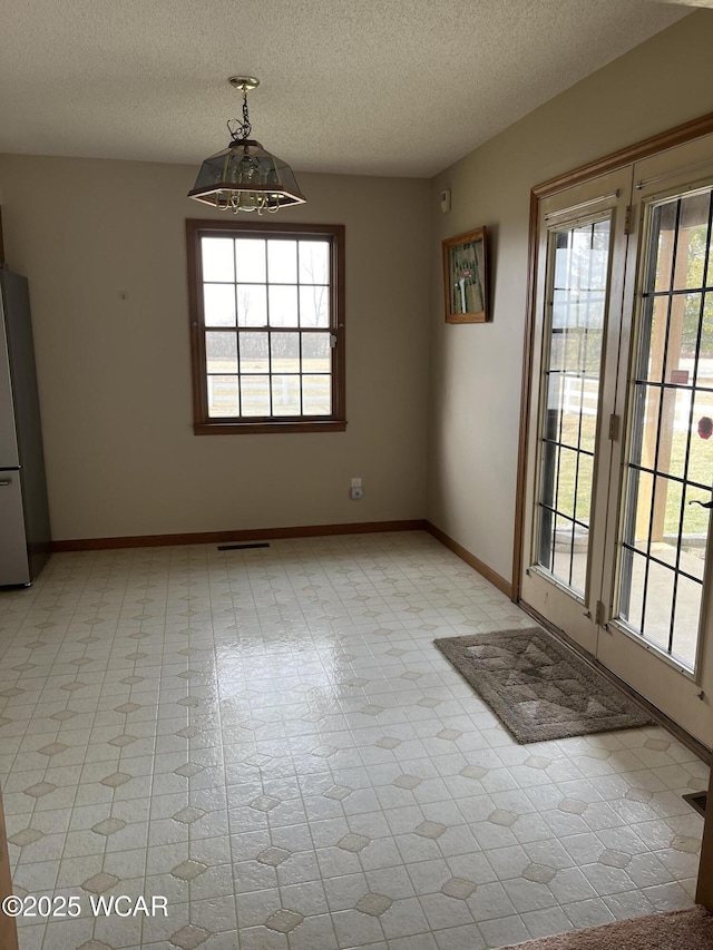 unfurnished dining area featuring plenty of natural light and a textured ceiling