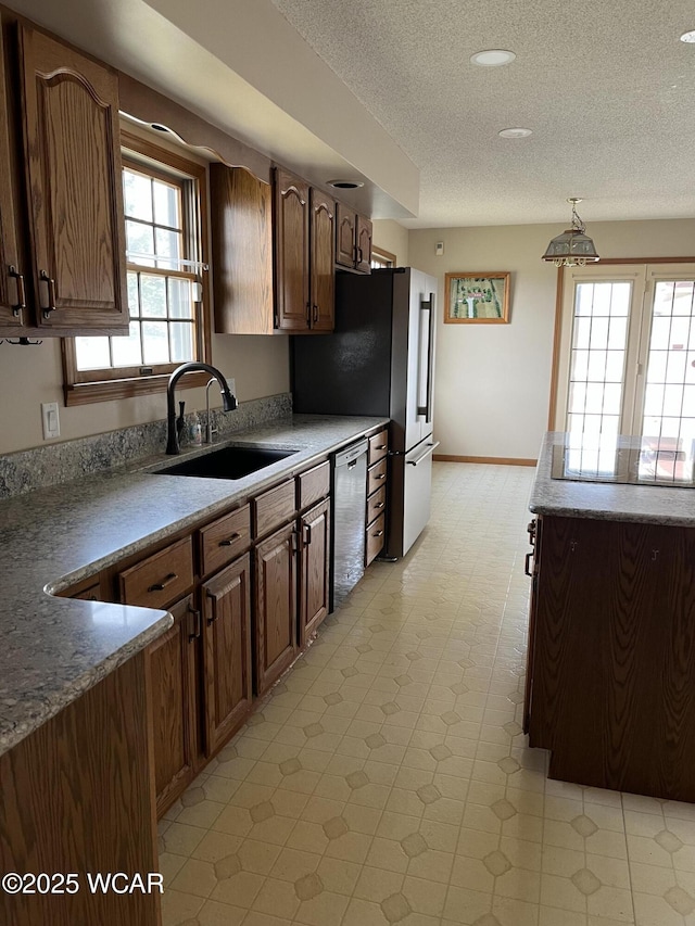 kitchen with sink, hanging light fixtures, a textured ceiling, and appliances with stainless steel finishes