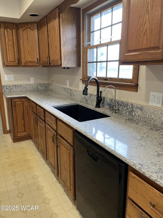 kitchen with black dishwasher, sink, and light stone countertops