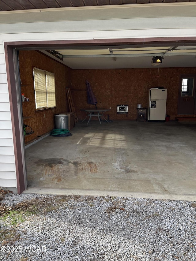 garage with a garage door opener and white fridge with ice dispenser