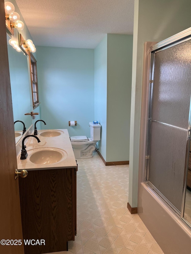 full bathroom featuring vanity, a textured ceiling, bath / shower combo with glass door, and toilet