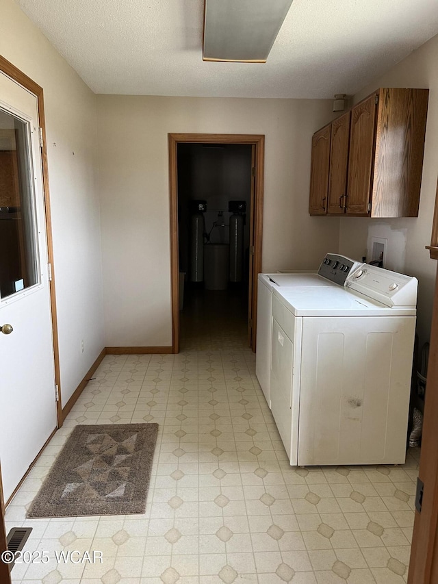 laundry area featuring independent washer and dryer, cabinets, and a textured ceiling