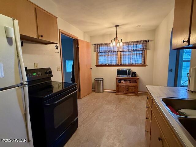 kitchen with a notable chandelier, black electric range, hanging light fixtures, freestanding refrigerator, and stainless steel microwave