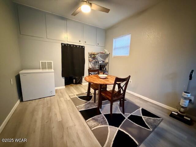 dining area featuring a ceiling fan, baseboards, visible vents, and light wood finished floors