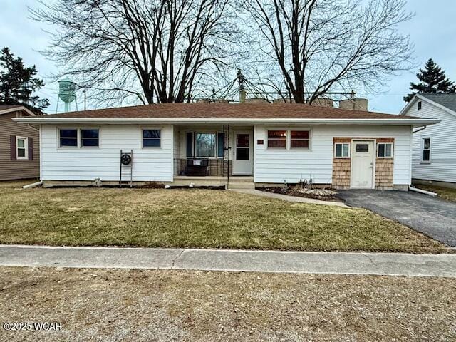 ranch-style house featuring covered porch, a chimney, aphalt driveway, and a front yard