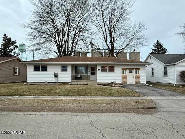 single story home featuring a chimney, aphalt driveway, and a front yard