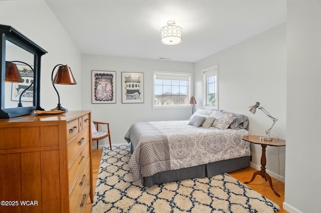 bedroom with light wood-style floors, baseboards, and visible vents