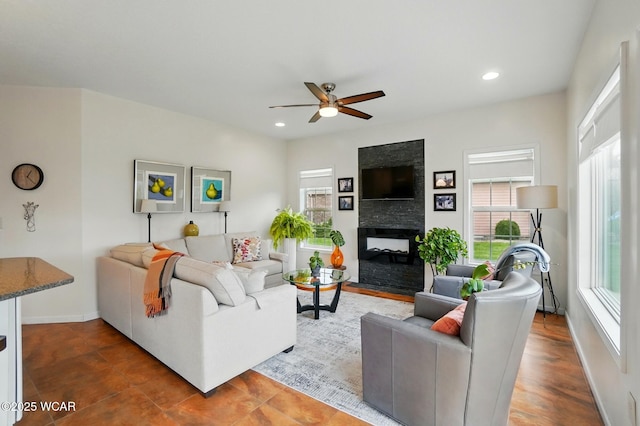 living room with a multi sided fireplace, a ceiling fan, baseboards, and recessed lighting