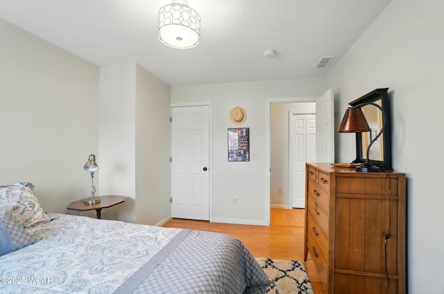 bedroom featuring baseboards, visible vents, and light wood finished floors