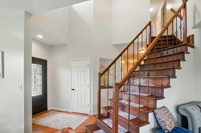 foyer entrance featuring baseboards, a high ceiling, stairs, and wood finished floors