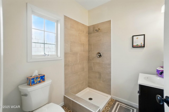 bathroom with vanity, baseboards, toilet, and tiled shower