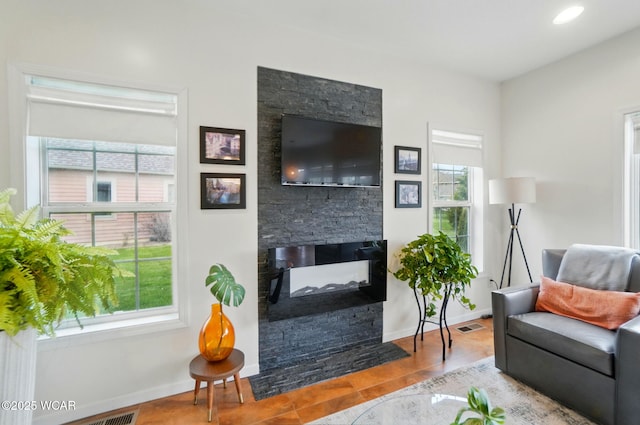 living room with baseboards, a fireplace, wood finished floors, and visible vents