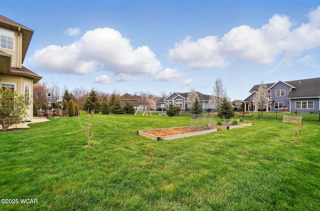 view of yard featuring a garden, fence, and a residential view