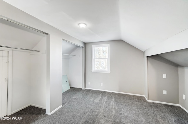 additional living space featuring dark carpet and vaulted ceiling