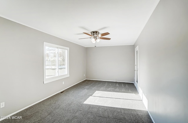 empty room with ceiling fan and dark carpet