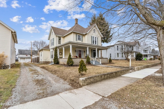 victorian home with a porch, an outbuilding, and a chimney