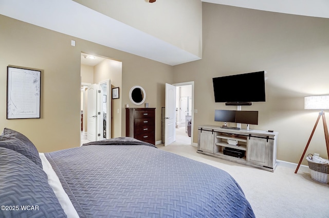 bedroom featuring ensuite bath, light colored carpet, and a high ceiling