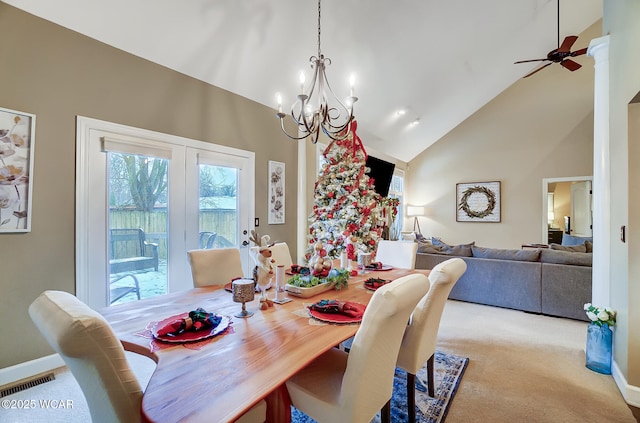 carpeted dining space with ceiling fan with notable chandelier and high vaulted ceiling